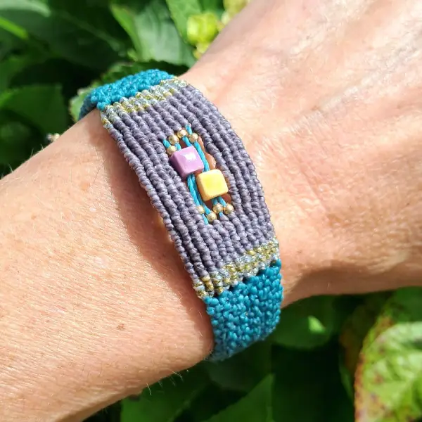 Bracelet en micro macramé, tissé avec plusieurs points vert et gris, avec incrustation de perles en céramique et en laiton.